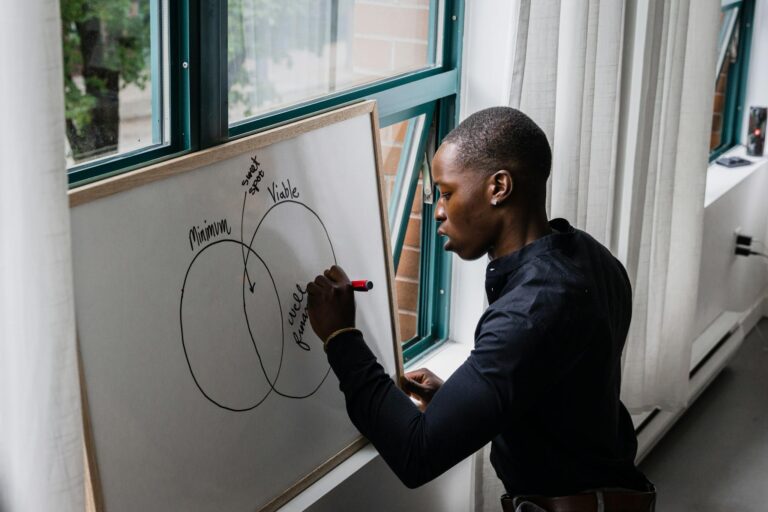 African American man writing on whiteboard with Venn diagram, indoors.